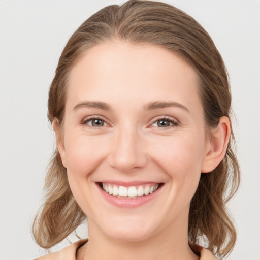 Joyful white young-adult female with medium  brown hair and grey eyes