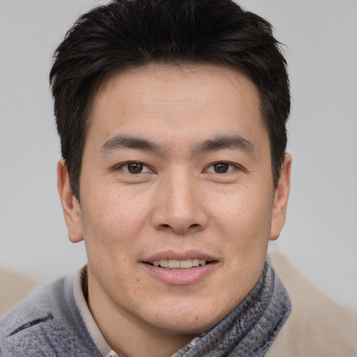Joyful asian young-adult male with short  brown hair and brown eyes