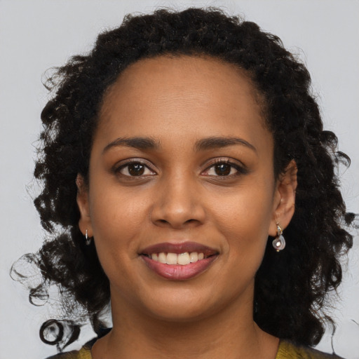 Joyful black young-adult female with long  brown hair and brown eyes
