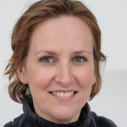 Joyful white adult female with medium  brown hair and blue eyes