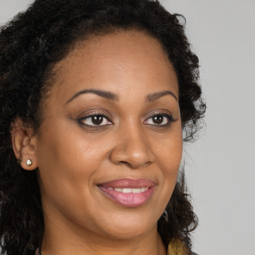 Joyful black young-adult female with long  brown hair and brown eyes