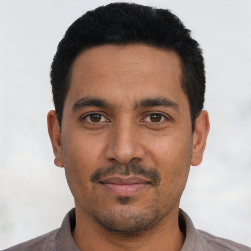 Joyful latino young-adult male with short  black hair and brown eyes