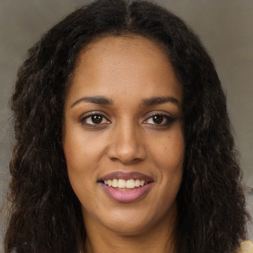 Joyful black young-adult female with long  brown hair and brown eyes