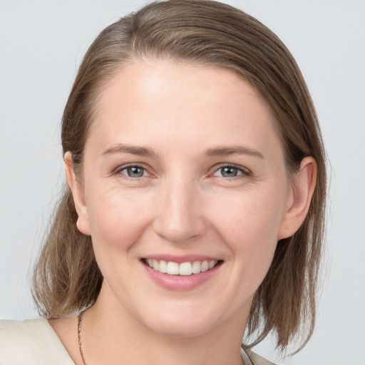 Joyful white young-adult female with medium  brown hair and grey eyes