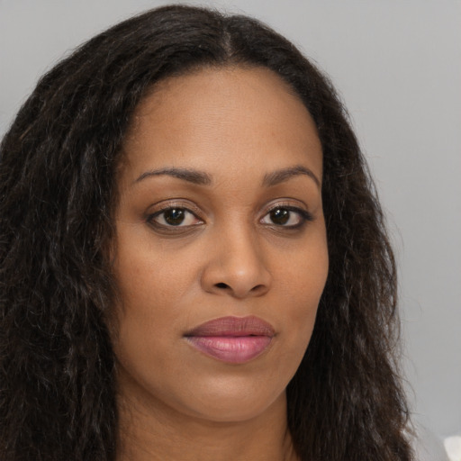 Joyful black young-adult female with long  brown hair and brown eyes