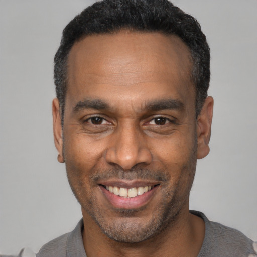 Joyful black adult male with short  black hair and brown eyes