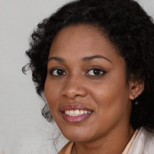 Joyful black young-adult female with long  black hair and brown eyes