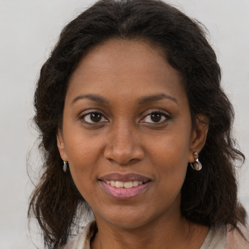 Joyful black adult female with long  brown hair and brown eyes