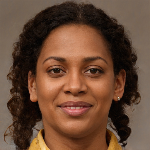 Joyful black young-adult female with long  brown hair and brown eyes