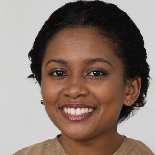 Joyful black young-adult female with short  black hair and brown eyes
