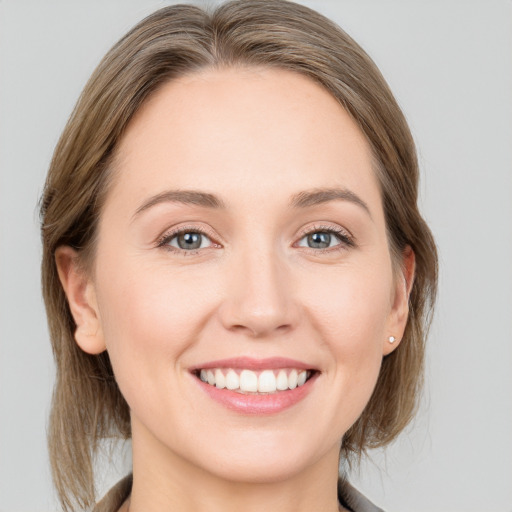 Joyful white young-adult female with medium  brown hair and grey eyes