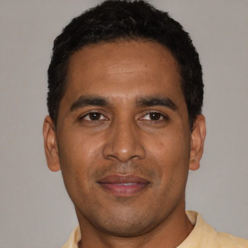 Joyful black young-adult male with short  brown hair and brown eyes
