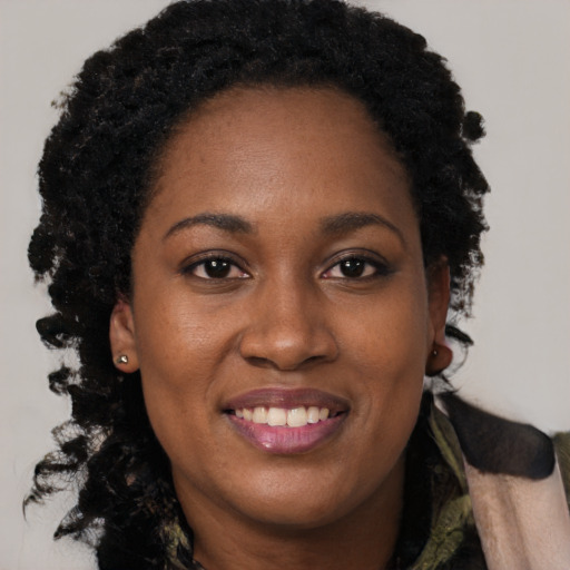 Joyful black young-adult female with long  brown hair and brown eyes