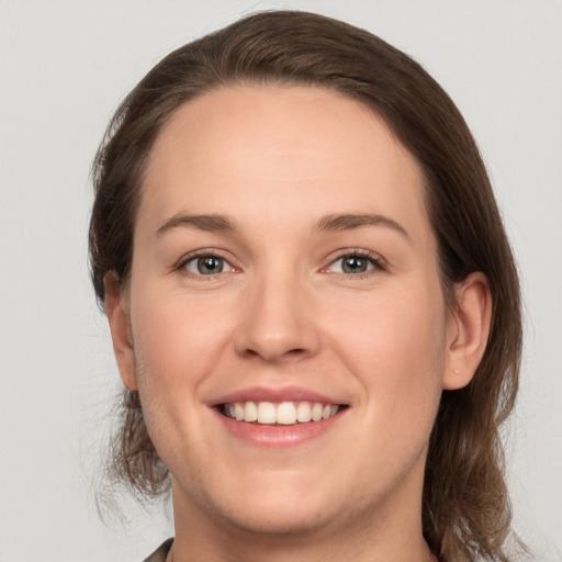 Joyful white young-adult female with medium  brown hair and grey eyes