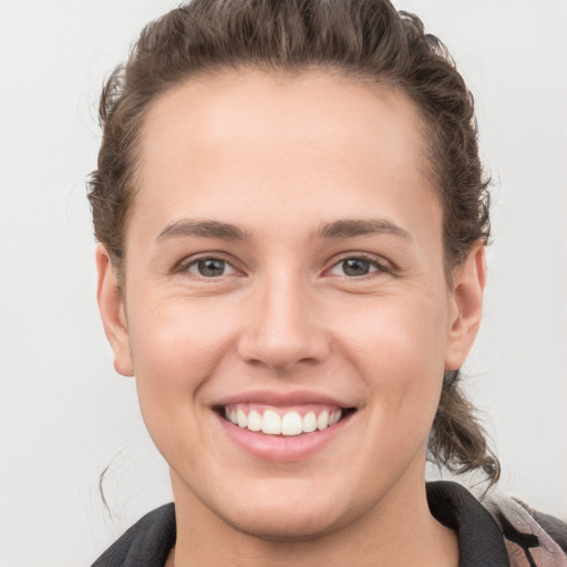 Joyful white young-adult female with short  brown hair and grey eyes