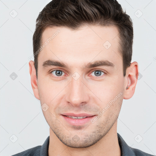 Joyful white young-adult male with short  brown hair and grey eyes