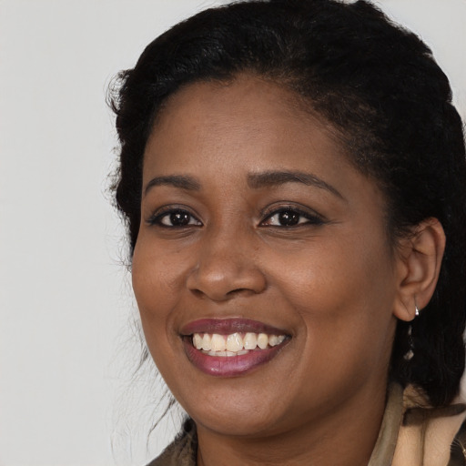 Joyful black young-adult female with long  black hair and brown eyes