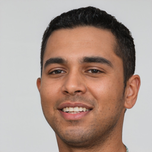 Joyful latino young-adult male with short  black hair and brown eyes