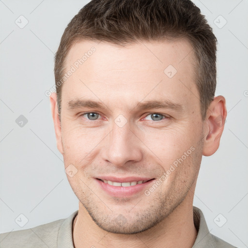 Joyful white young-adult male with short  brown hair and grey eyes