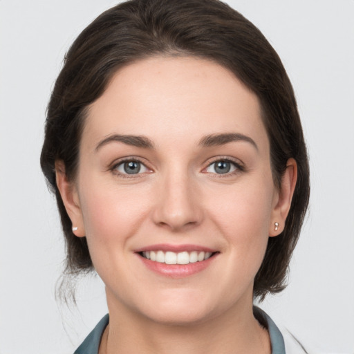 Joyful white young-adult female with medium  brown hair and grey eyes