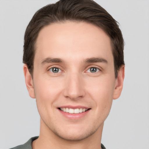 Joyful white young-adult male with short  brown hair and grey eyes