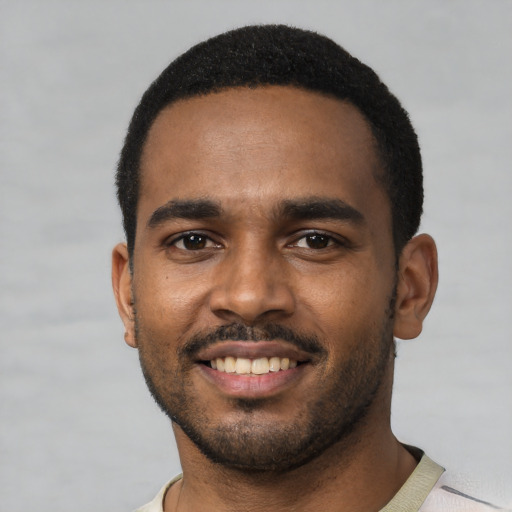Joyful black young-adult male with short  black hair and brown eyes
