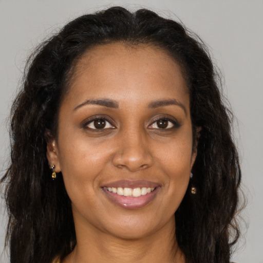 Joyful black young-adult female with long  brown hair and brown eyes