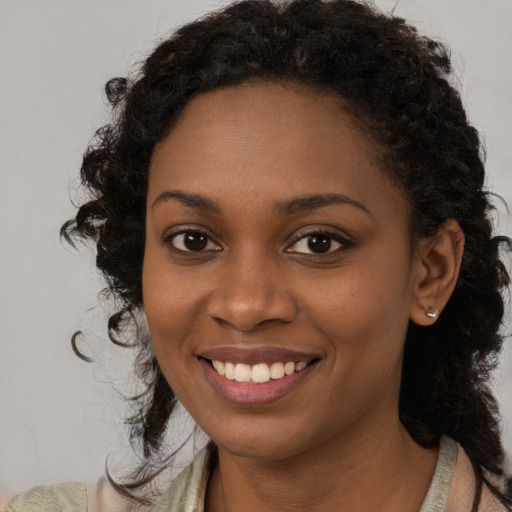 Joyful black young-adult female with long  black hair and brown eyes