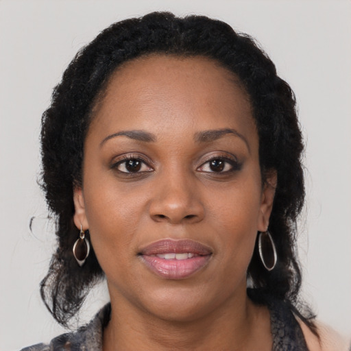 Joyful black young-adult female with long  black hair and brown eyes