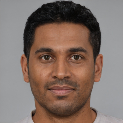 Joyful black young-adult male with short  black hair and brown eyes