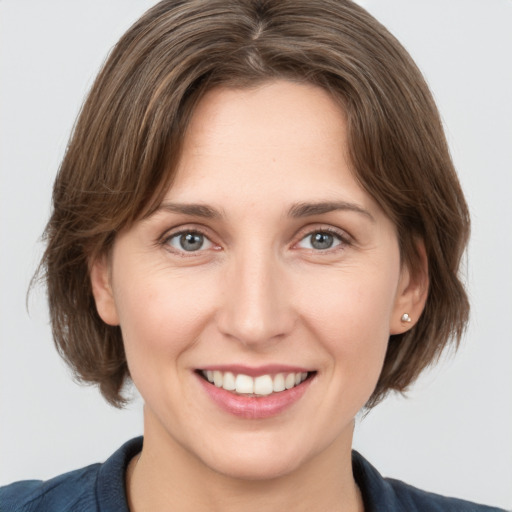 Joyful white young-adult female with medium  brown hair and grey eyes