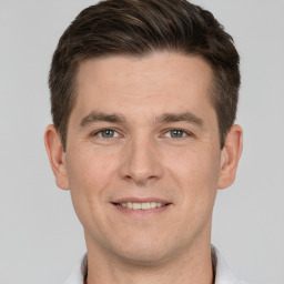 Joyful white young-adult male with short  brown hair and grey eyes