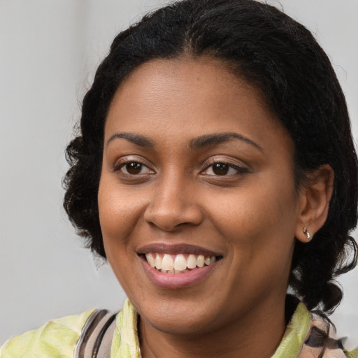 Joyful black young-adult female with long  brown hair and brown eyes