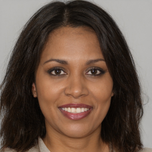 Joyful black young-adult female with long  brown hair and brown eyes