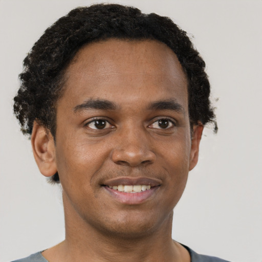 Joyful black young-adult male with short  brown hair and brown eyes