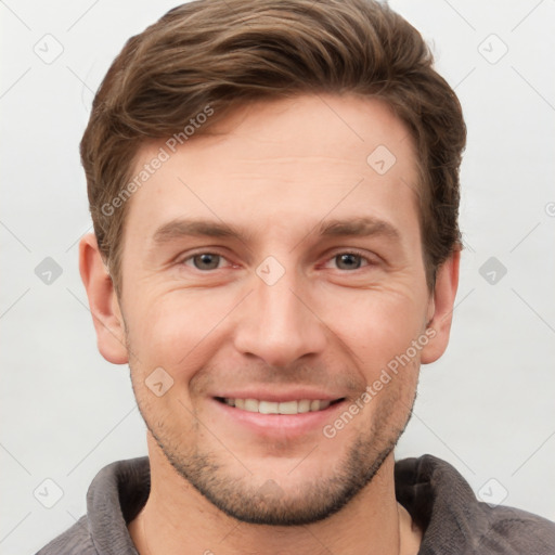 Joyful white young-adult male with short  brown hair and grey eyes