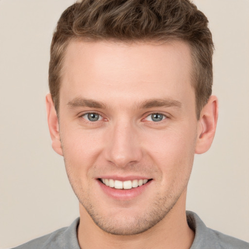 Joyful white young-adult male with short  brown hair and grey eyes