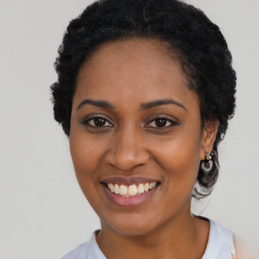 Joyful black young-adult female with short  black hair and brown eyes