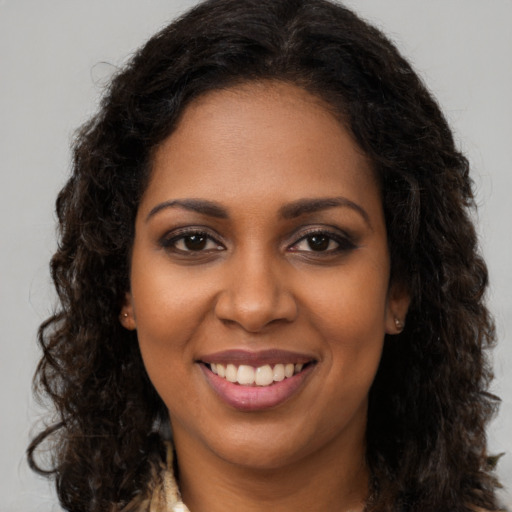 Joyful black young-adult female with long  brown hair and brown eyes
