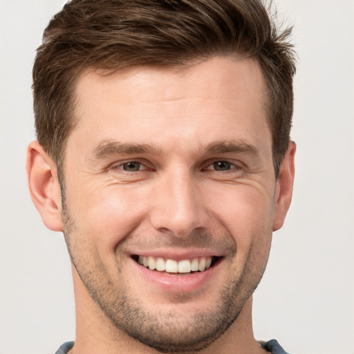 Joyful white young-adult male with short  brown hair and grey eyes