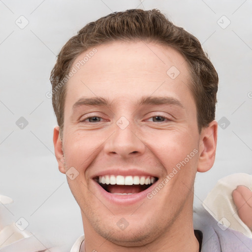 Joyful white young-adult male with short  brown hair and grey eyes