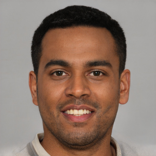 Joyful black young-adult male with short  black hair and brown eyes