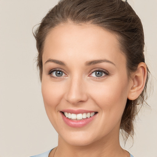 Joyful white young-adult female with medium  brown hair and grey eyes