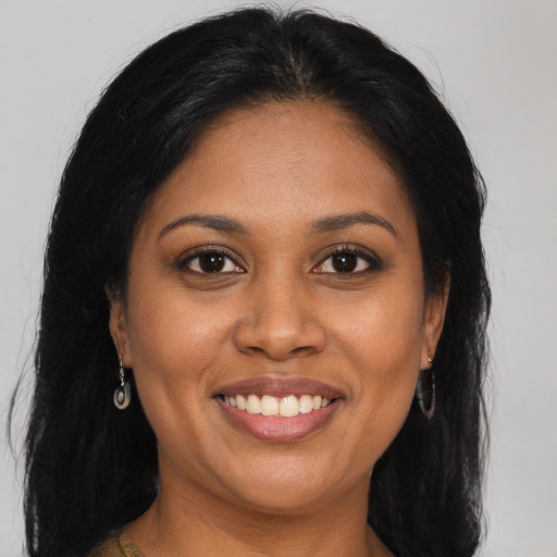 Joyful black adult female with long  brown hair and brown eyes
