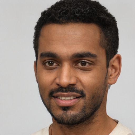 Joyful black young-adult male with short  black hair and brown eyes