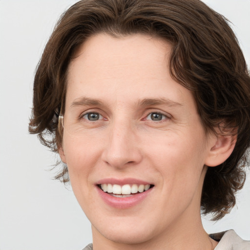 Joyful white young-adult female with medium  brown hair and green eyes