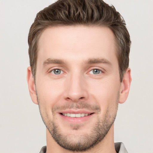 Joyful white young-adult male with short  brown hair and grey eyes