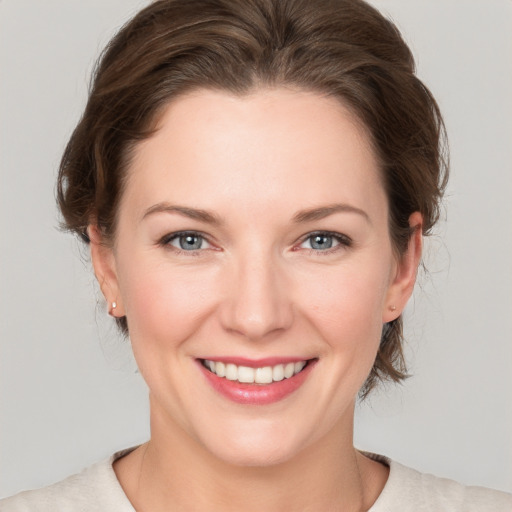 Joyful white young-adult female with medium  brown hair and grey eyes