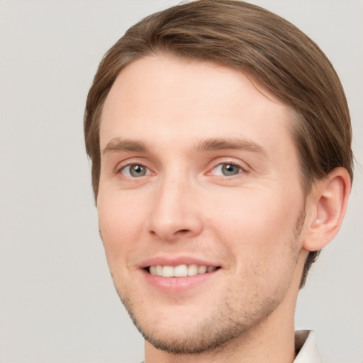 Joyful white young-adult male with short  brown hair and grey eyes