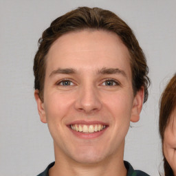 Joyful white young-adult male with short  brown hair and grey eyes